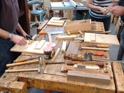 De werkbank ligt vol met hout waar aan gewerkt wordt